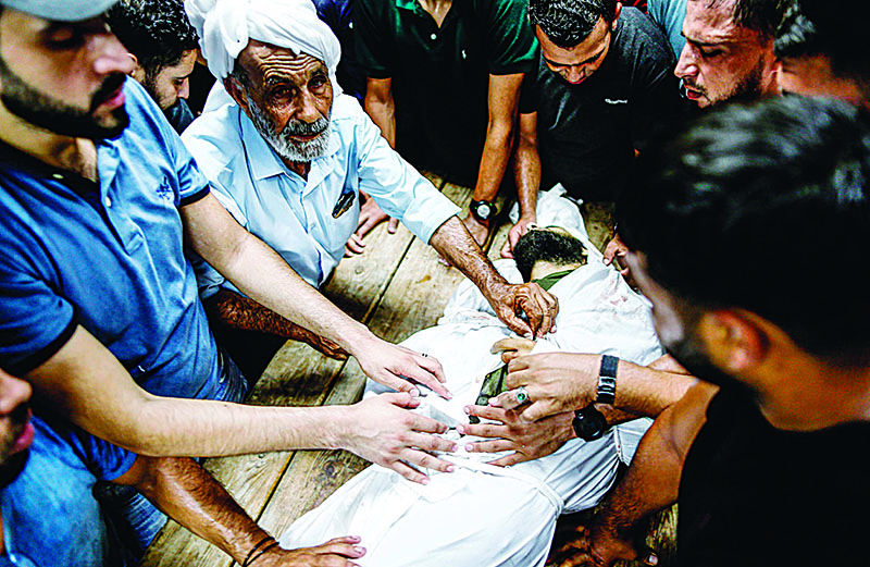 Relatives of 26-year-old Palestinian Mohammed Samir al-Taramsi, one of three armed Palestinians killed overnight in Israeli fire along the border with the Gaza Strip, mourn by his body at the morgue of the hospital in Beit Lahya in northern Gaza strip on August 18, 2019. - Israel said it opened fire on armed Palestinians on Gaza's border overnight and Hamas's health ministry reported three dead on August 18, the latest in a series of incidents along the tense barrier. Israel's tank and helicopter fire came after Palestinian militants in the Gaza Strip fired three rockets at Israel late the previous day, the army said, the second such attack in 24 hours. (Photo by MAHMUD HAMS / AFP)