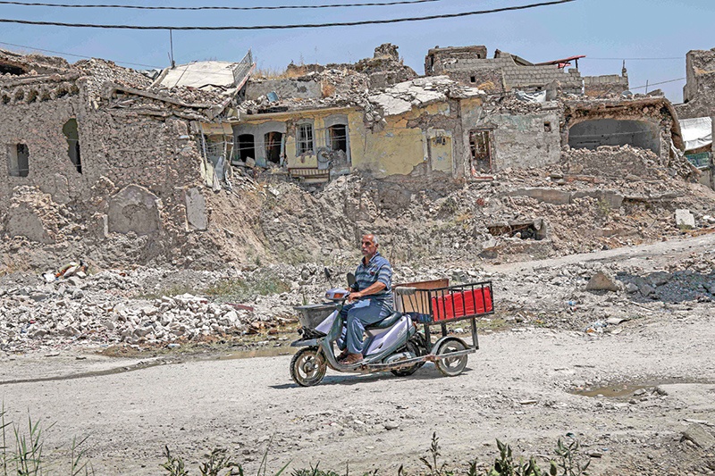 A man rides a scooter cart along a damaged street in the western part of Iraq's northern city of Mosul on August 10, 2019. - Although Mosul was freed from the grip of Islamic State (IS) group jihadists in 2017, tens of thousands of displaced Iraqis native to the city remain dwelling in sprawling displacement camps instead of moving back home to its unlivable ruins. Many of them say they tried returning but were shocked by what they saw. Across Iraq, more than 1.6 million people remain displaced, among them nearly 300,000 from Mosul alone, according to the International Organization for Migration. (Photo by SAFIN HAMED / AFP)