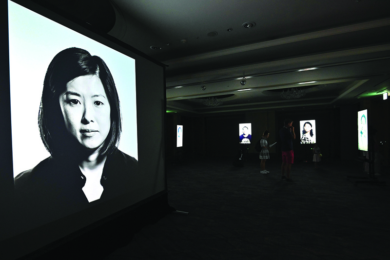 TOPSHOT - This picture taken on July 31, 2019 shows visitors looking at a film project on adoption in South Korea, Side x Side, directed by Korean-American adoptee Glenn Morey at a exhibition hall in Seoul. - International adoption from South Korea began after the Korean War as a way to remove mixed-race children, born to Korean mothers and American GI fathers, from an ethnically homogenous country with widespread racism. More recently the main driver has been babies born to unmarried women, who still face stigmatisation in a patriarchal society. (Photo by Jung Yeon-je / AFP) / TO GO WITH SKorea-social-adoption-migration-film,FEATURE by Claire LEE