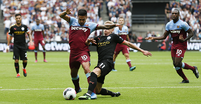Manchester City's Ukrainian midfielder Oleksandr Zinchenko (CR) tackles West Ham United's Argentinian midfielder Manuel Lanzini (CL) during the English Premier League football match between West Ham United and Manchester City at The London Stadium, in east London on August 10, 2019. (Photo by Ian KINGTON / AFP) / RESTRICTED TO EDITORIAL USE. No use with unauthorized audio, video, data, fixture lists, club/league logos or 'live' services. Online in-match use limited to 120 images. An additional 40 images may be used in extra time. No video emulation. Social media in-match use limited to 120 images. An additional 40 images may be used in extra time. No use in betting publications, games or single club/league/player publications. /
