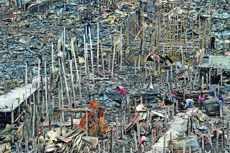 TOPSHOT - A resident gathers charred debris in a slum in Dhaka on August 18, 2019, after a fire broke out late on August 17 at Mirpur neighbourhood. - At least 10,000 people are homeless after a massive fire swept through a crowded slum in the Bangladesh capital and destroyed thousands of shanties, officials said on August 18. (Photo by MUNIR UZ ZAMAN / AFP)