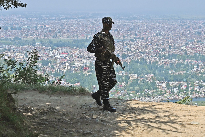 An Indian paramilitary trooper patrols at the top of a hill in Srinagar on August 25, 2019. (Photo by Tauseef MUSTAFA / AFP)