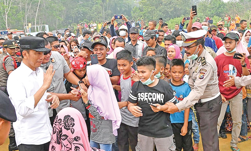 PEKANBARU: Indonesian President Joko Widodo meets children while inspecting the damages from the ongoing forest fires in Pekanbaru. — AFP