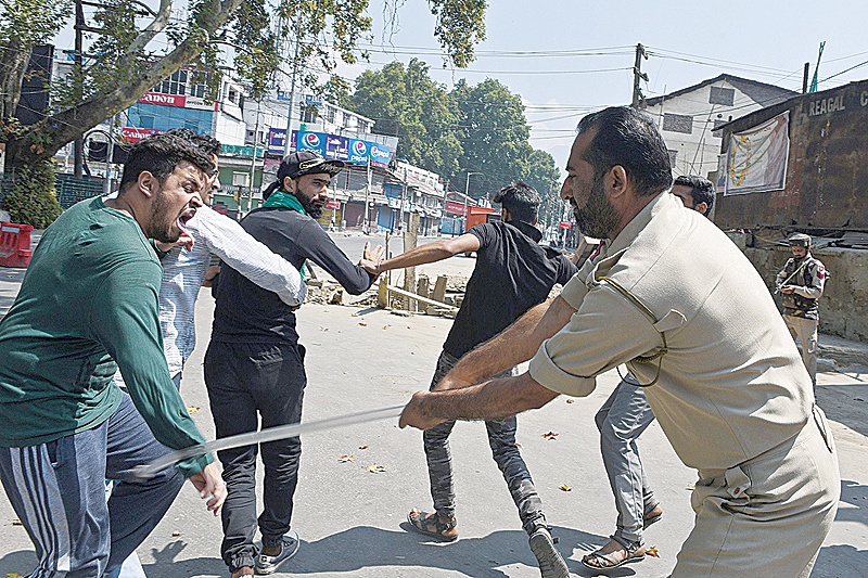 KASHMIR: An Indian policeman clashes with Indian Kashmiri Shiite during a strict curfew in Lal Chowk area of Srinagar on the 8th day of Muharram yesterday. —AFP