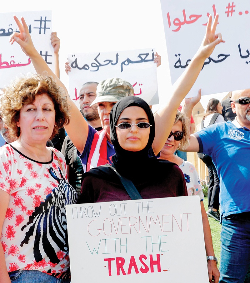 BEIRUT: Lebanese protesters hold placards during a demonstration in Martyrs' Square yesterday. - AFP 