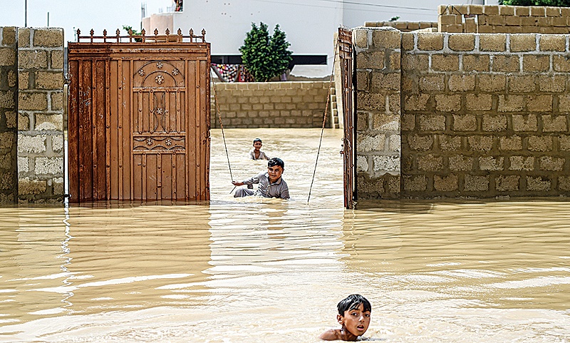 KARACHI: Young boys wade and play among floodwaters during heavy monsoon rains. —AFP