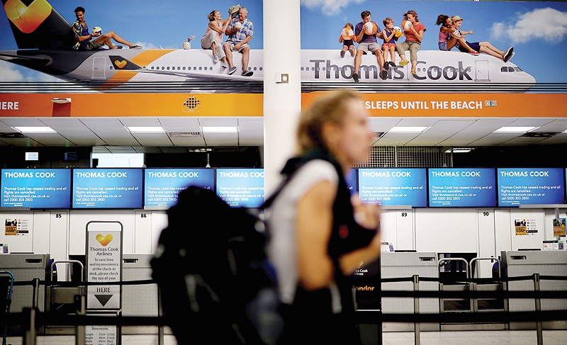 Passengers walk past closed Thomas Cook check-in desks at the South Terminal of London Gatwick Airport in Crawley yesterday. – AFP  