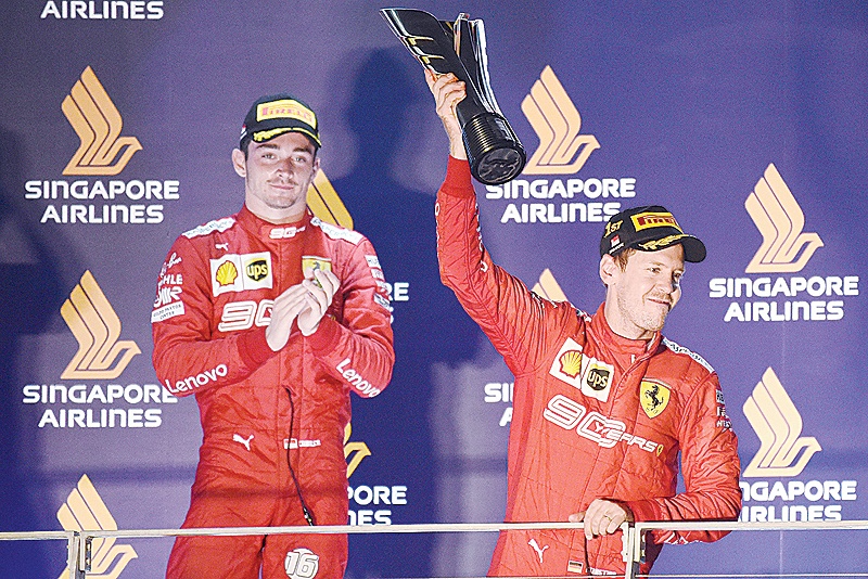 SINGAPORE: Ferrari's German driver Sebastian Vettel (R) holds up the trophy as second-placed Ferrari's Monegasque driver Charles Leclerc (L) looks on, after the Formula One Singapore Grand Prix night race at the Marina Bay Street Circuit in Singapore yesterday. – AFP