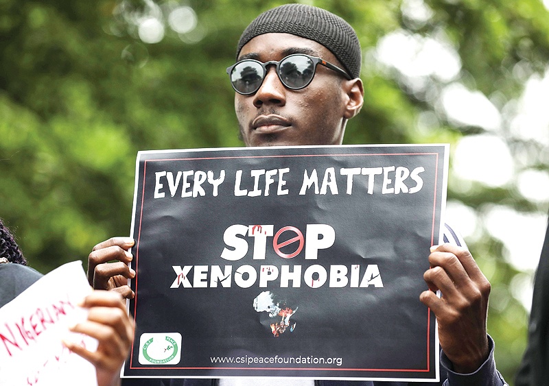 ABUJA: A demonstrator holds a sign during a protest against xenophobia outside of the main gate of the South African High Commission which was shut down to avert reprisal attacks in Abuja. —AFP