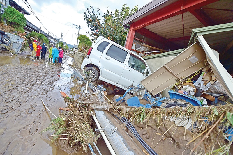 A car sits next to a badly damaged home in Nagano on October 15, 2019, after Typhoon Hagibis hit Japan on October 12 unleashing high winds, torrential rain and triggered landslides and catastrophic flooding. - The death toll from the disaster has risen steadily, and the national broadcaster early on October 15 said 58 people had been killed, according to authorities, while more than a dozen were still missing. (Photo by Kazuhiro NOGI / AFP)