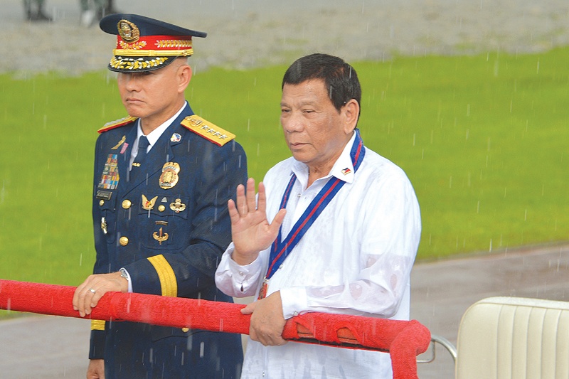 MANILA: This file photo taken on August 8, 2018 shows Philippine President Rodrigo Duterte (R) reviewing policemen along with national police chief Oscar Albayalde (L) in a sudden downpour during the 117th police anniversary celebration at the national headquarters. — AFP