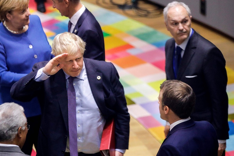 British Prime Minister Boris Johnson (C) gestures as he salutes French President Emmanuel Macron (front R) as he arrives for a round table meeting as part of a European Union summit at European Union Headquarters in Brussels on October 17, 2019. - Britain and the European Union reached a new divorce deal on October 17, 2019 that could allow Brexit on October 31, but faced immediate opposition among MPs in London -- who can still block it. - AFP