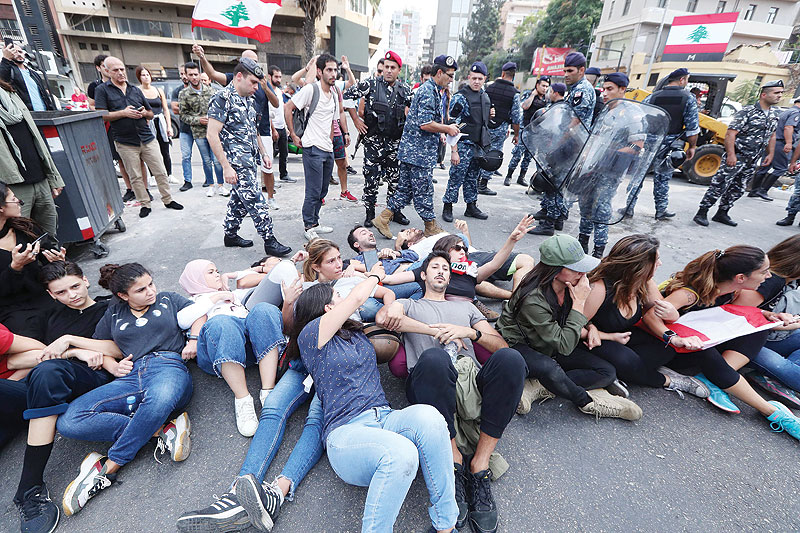 BEIRUT: Members of the Lebanese security forces surround protesters blocking a major bridge in the center of the capital during an anti-government protest yesterday. — AFP