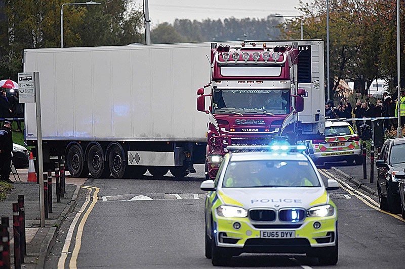 GRAYS: Police officers drive away a lorry in which was discovered 39 dead bodies, at Waterglade Industrial Park in Grays, east of London. —AFP