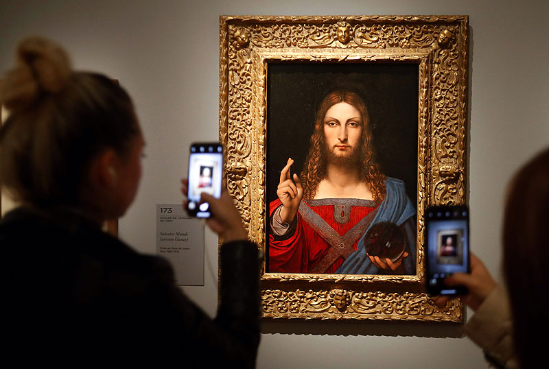 People take pictures with mobile phone at an oil painting by Atelier Leonardo da Vinci’s ‘Salvator Mundi’ (Version Ganay), during the opening of the exhibition ‘Leonardo da Vinci’, at the Louvre museum in Paris. — AFP