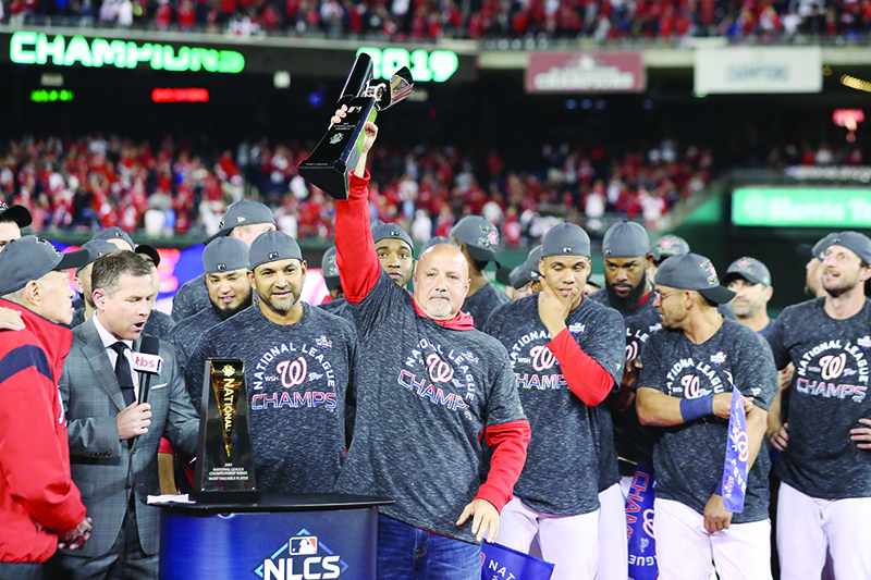 WASHINGTON, DC - OCTOBER 15: General manager Mike Rizzo and Manager Dave Martinez #4 of the Washington Nationals celebrate with the trophy after winning game four and the National League Championship Series against the St. Louis Cardinals at Nationals Park on October 15, 2019 in Washington, DC.   Rob Carr/Getty Images/AFP