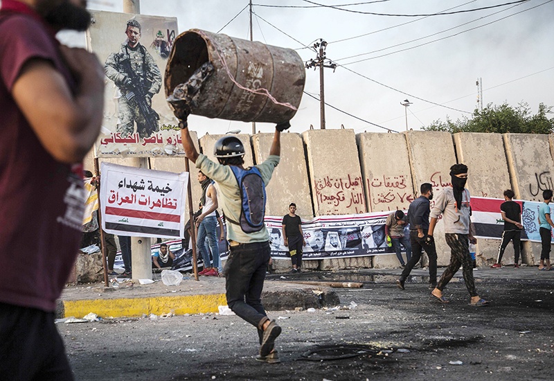 An Iraqi protester lifts a barrel as he takes part in an anti-goverment demonstration in the southern city of Basra on November 8, 2019. - Anti-government protests in Iraq entered their third week today amid fresh bloodshed.nIn Basra, seven protesters were killed in confrontations yesterday and early today, with security forces trying to reopen roads blocked by sit-ins, medical sources said. (Photo by Hussein FALEH / AFP)