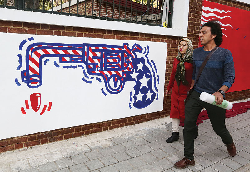 TEHRAN: Iranians walk past a new mural painted on the walls of the former US embassy in the capital Tehran yesterday. - AFP 