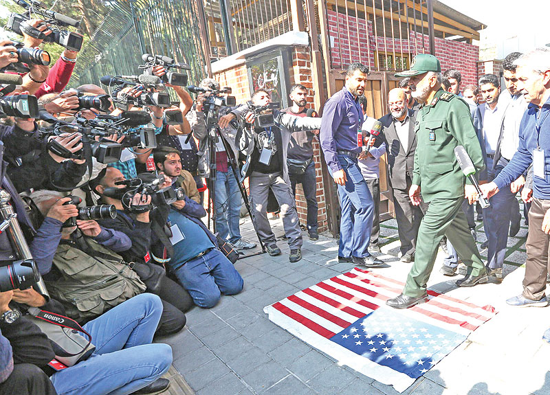 TEHRAN: Iranian Revolutionary Guards commander Major General Hossein Salami (right) steps on a US flag upon his arrival to attend a ceremony organized to unveil the new murals painted on the walls of former US embassy in the capital Tehran yesterday. — AFP