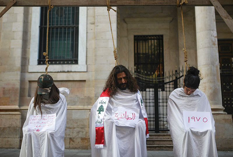 BAABDA: Lebanese protesters stage a mock hanging in a symbolic performance against sectarianism (center), Lebanon’s 1975-90 civil war (right) and corruption during ongoing anti-government demonstrations in Downtown Beirut yesterday.—AFP