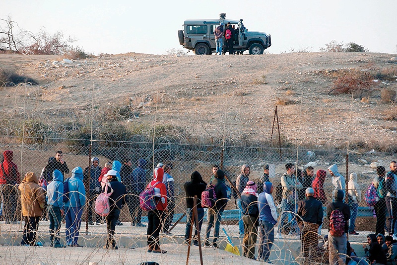 BEERSHEBA: Palestinian laborers wait for an Israeli police vehicle to leave in order to cross illegally into Israeli areas through a hole in Israel's illegal barrier wall on Nov 20, 2019. - AFP 