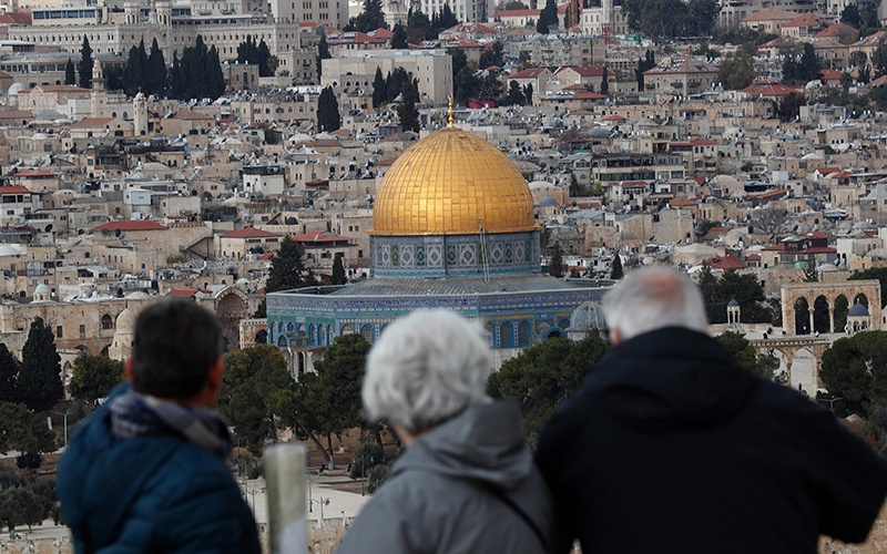 JERUSALEM: Tourists look at the Old City of Jerusalem and its Dome of the Rock Mosque from the Mount of Olives on Friday. — AFP