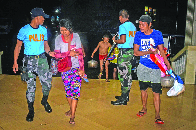 Police assist residents arriving at an evacuation centre, as typhoon Phanfone makes landfall, in Borongan, Eastern Samar province, central Philippines on December 24, 2019. - Typhoon Phanfone smashed into the central Philippines on December 24, leaving thousands of people unable to get home for the Christmas holidays and forcing many others to evacuate in the face of the onslaught. (Photo by ALREN BERONIO / AFP)