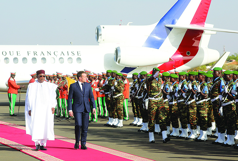 France's President Emmanuel Macron (C) reviews troops as he is greeted by Niger's President Mahamadou Issoufou (L) at the Diori Hamani International Airport, on December 22, 2019, in Niamey, as part of a three-day visit to West Africa. (Photo by Ludovic MARIN / POOL / AFP)
