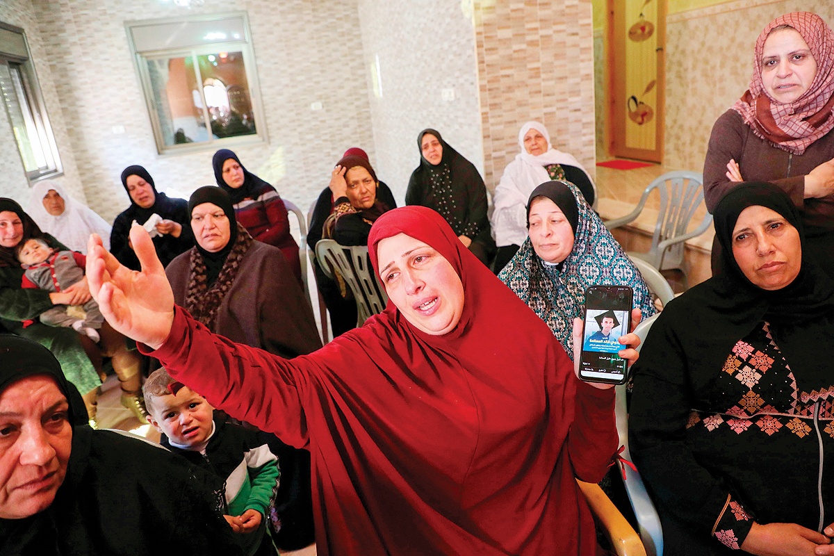 BAYT AWWA: Hanan, the mother of 18-year-old Badawee Masalma, shows a picture of him on her phone during his funeral in this West Bank village southwest of Hebron yesterday. - AFP 