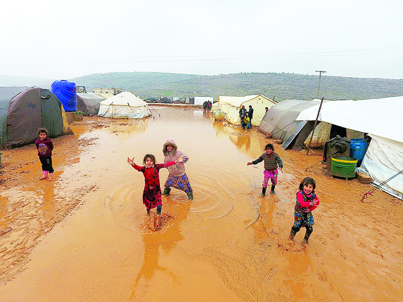 An aerial photograph shows children playing near tents sheltering Syrians who fled ongoing battles in the southern and eastern coutryside of the Idlib province, surrounded by mud caused by heavy rain, in a camp for displaced people near Sarmada near the border with Turkey in the northern part of the province on December 29, 2019. (Photo by Aref TAMMAWI / AFP)