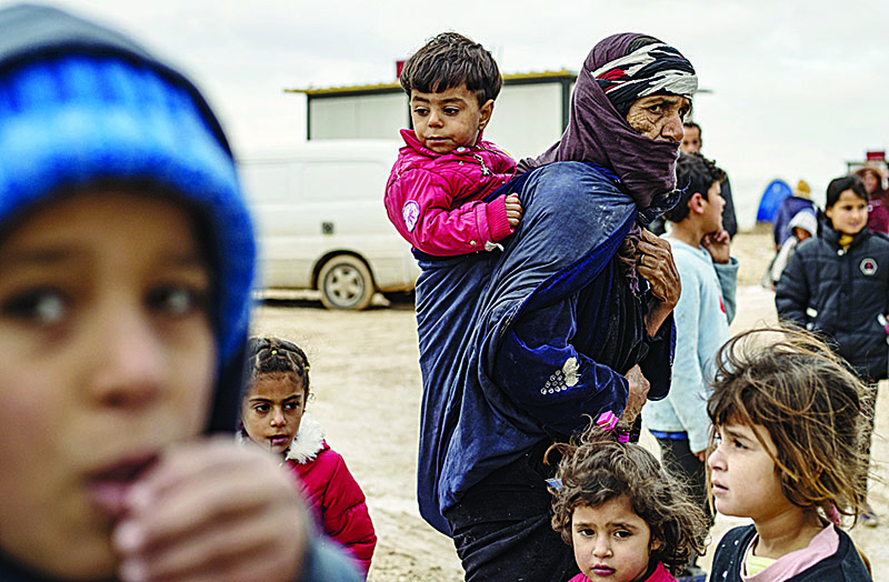 An elderly Syrian woman carries a toddler as others gather at the Washukanni camp for internally displaced persons (IDP) in the mainly Kurdish northeastern Syrian province of Hasakeh on December 27, 2019. - Since a Turkish assault in northeastern Syria some 300,000 people have been displaced, according to the Syrian Observatory for Human Rights. (Photo by Delil SOULEIMAN / AFP)