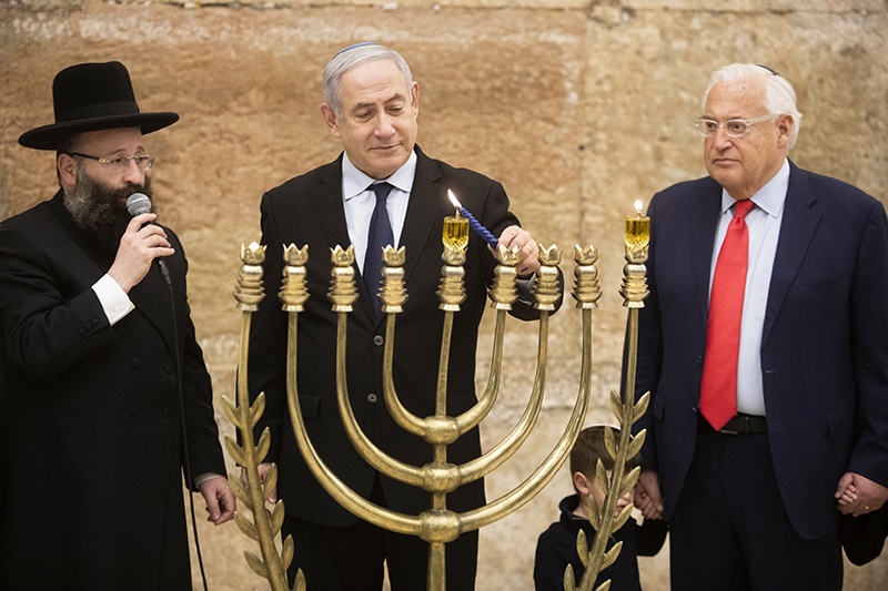 Israeli Prime Minister Benjamin Netanyahu lights a Hanukkah candle alongside the Rabbi of the Western Wall Shmuel Rabinovitch (L) and US ambassador to Israel David Friedman at the Western Wall, Judaism's holiest prayer site, in the Old City of Jerusalem on December 22, 2019. (Photo by Sebastian Scheiner / POOL / AFP)
