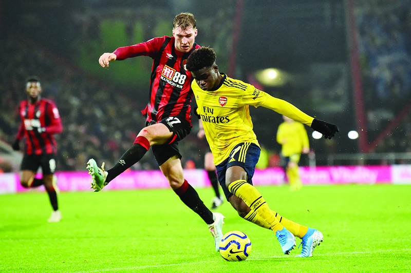 Bournemouth's English defender Jack Stacey (L) vies with Arsenal's English striker Bukayo Saka during the English Premier League football match between Bournemouth and Arsenal at the Vitality Stadium in Bournemouth, southern England on December 26, 2019. (Photo by Glyn KIRK / AFP) / RESTRICTED TO EDITORIAL USE. No use with unauthorized audio, video, data, fixture lists, club/league logos or 'live' services. Online in-match use limited to 120 images. An additional 40 images may be used in extra time. No video emulation. Social media in-match use limited to 120 images. An additional 40 images may be used in extra time. No use in betting publications, games or single club/league/player publications. /