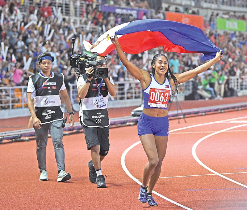 CLARK: Kristina Marie Knott (C) from the Philippines celebrates after winning in the women's 200m athletics event at the SEA Games (Southeast Asian Games) at the athletics stadium in Clark, Capas, Tarlac province north of Manila yesterday. - AFP