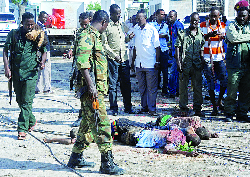 EDITORS NOTE: Graphic content / (FILES) In this file photo taken on June 26, 2016 Somali soldiers and people stand and look at the bodies of three suspected fighters of the radical Islamist al-Shabab group lying in the road outside The Nasahablood Hotel in Mogadishu, a day after an attack in which at least 11 people were killed. - In the past decade 2010-2019 Somali Islamist group Al-Shabaab has lost territory, suffered defections and faced increased US air strikes, but analysts say the group is as strong a threat as ever, flourishing under a weak government. Despite years of expensive efforts to combat the group, Al-Shabaab managed once again to detonate a vehicle packed with explosives in Mogadishu, massacring 81 people on Saturday in one of the deadliest attacks of the decade. (Photo by Mohamed Abdiwahab / AFP)