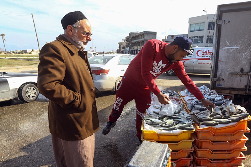A man buys fresh fish from a stall in the Libyan capital Tripoli on January 13, 2020. - Residents of Libya's capital have received news of a ceasefire with a mix of relief and scepticism after more than nine months of deadly fighting on the edges of Tripoli (Photo by Mahmud TURKIA / AFP)