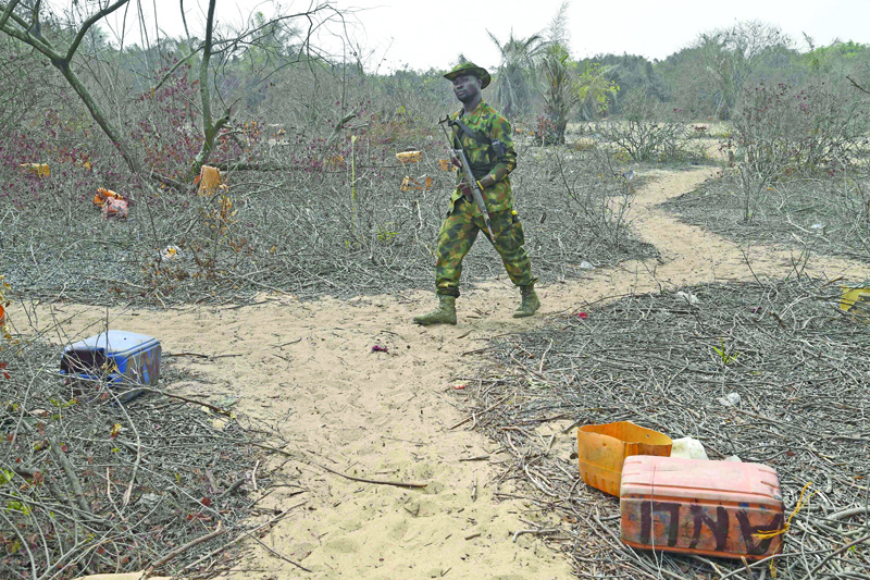 A naval personnel walk past jerrycans abandoned by vandals stealing from oil pipelines belonging to the Nigerian National Petroleum Company (NNPC) close to Tarkwa Bay, near Lagos' harbour on January 23, 2020. - The Nigerian navy personnel shot in the air on January 21, 2020, as they sought to clear a waterfront community of 10,000 people in the latest mass-eviction around economic hub Lagos.Bulldozers rumbled into Tarkwa Bay, a semi-rural area on an island in the city of some 20 million, as part of an operation the military say is aimed officially at stopping the looting of nearby oil pipelines. (Photo by PIUS UTOMI EKPEI / AFP)