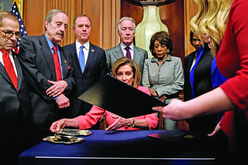 Speaker of the House Nancy Pelosi (D-CA) (C) is handed a document while signing the articles of impeachment of US President Donald Trump during an engrossment ceremony on Capitol Hill January 15, 2020, in Washington, DC. - The US House of Representatives voted Wednesday to transmit articles of impeachment against President Donald Trump to the Senate, opening the way for the historic trial of the 45th president for abuse of power. (Photo by Brendan Smialowski / AFP)