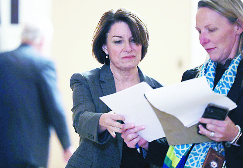 WASHINGTON, DC - JANUARY 24: Democratic Presidential Candidate Sen. Amy Klobuchar (D-MN) (C) goes through papers with in aide outside the Senate chamber during a recess in the impeachment trial proceedings against President Donald Trump at the U.S. Capitol on January 24, 2020 in Washington, DC. House Democrats will wrap up opening arguments on day 4 of the Senate impeachment trial.   Mario Tama/Getty Images/AFP