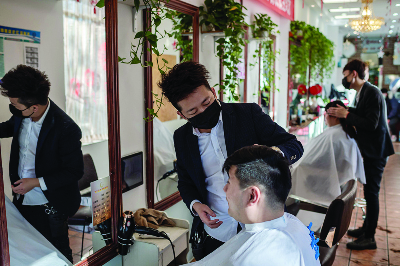 TOPSHOT - Hairdressers wear protective masks as they cut the hair of customers in Beijing on January 23, 2020. - Seventeen people have died and more than 570 people have been infected with the new SARS-like virus across China -- with most cases found in Wuhan, where a seafood market that illegally sold wild animals has been identified as the epicentre of the outbreak. (Photo by NICOLAS ASFOURI / AFP)