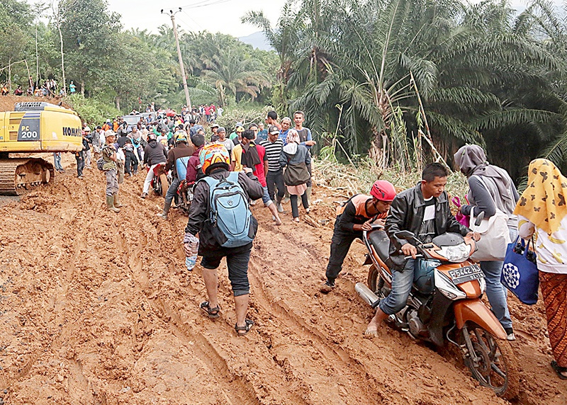 Villagers commute through the mud in a landslide area at Sukaraksa village in Bogor, after torrential rains began to hit the area on December 31. - Indonesian rescue teams flew helicopters stuffed with food to remote flood-hit communities on January 4 as the death toll from the disaster jumped to 53 and fears grew about the possibility of more torrential rain. (Photo by TJAHYADI ERMAWAN / AFP)