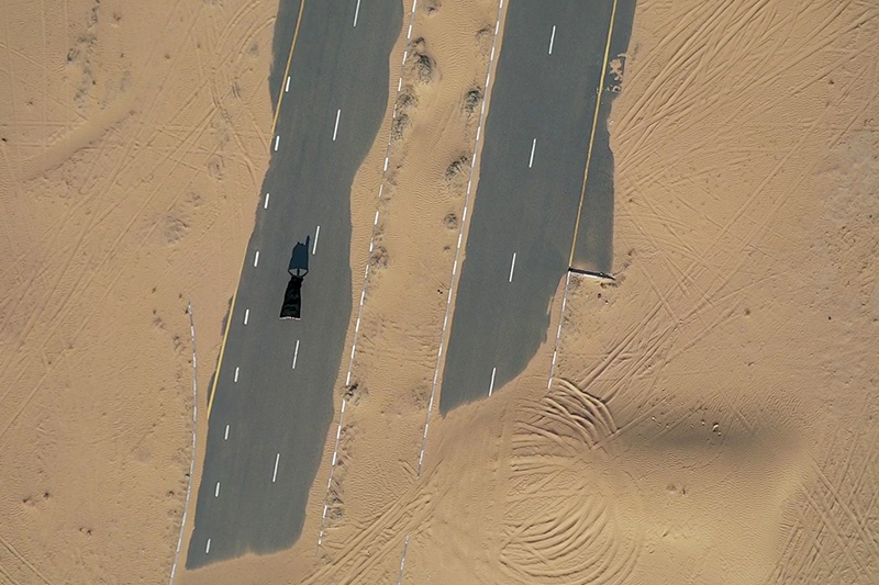 A drone picture taken on January 4, 2020 shows a model posing on a desert road in Dubai. (Photo by GIUSEPPE CACACE / AFP)