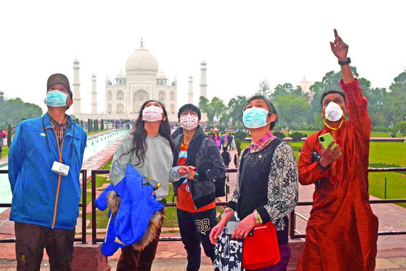 Chinese tourists, wearing protective face masks, listen to their guide during a group tour visit at the Taj Mahal in Agra om January 28, 2020. - The epidemic, which experts believe emanated from a wild animal market in the city of Wuhan last month, has spread around China and to more than a dozen other countries despite the extraordinary travel curbs. (Photo by Pawan Sharma / AFP)