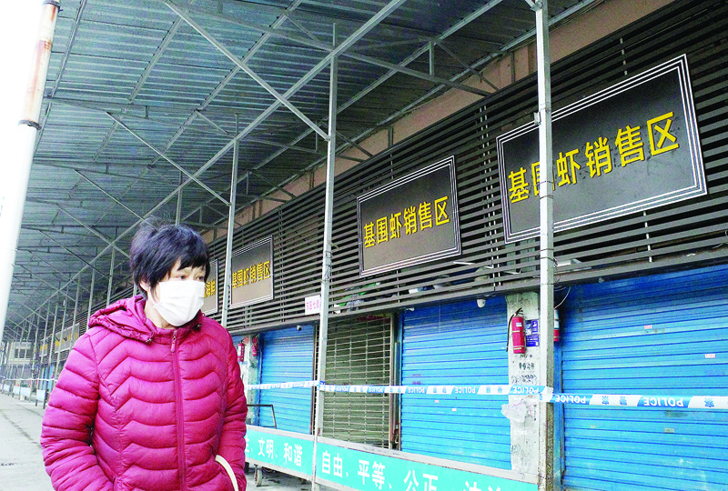 A woman walks in front of the closed Huanan wholesale seafood market, where health authorities say a man who died from a respiratory illness had purchased goods from, in the city of Wuhan, Hubei province, on January 12, 2020. - A 61-year-old man has become the first person to die in China from a respiratory illness believed caused by a new virus from the same family as SARS, which claimed hundreds of lives more than a decade ago, authorities said. (Photo by Noel Celis / AFP)