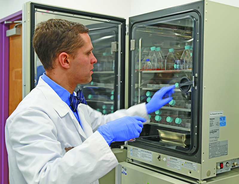 Dr. Michael Keller, an immunologist and Assistant Professor at Children's National Hospital, picks up a T-cell research sample from an incubator as he explains a new kind of tailored treatment during an interview with AFP on December 12, 2019 in Washington, DC. - Dr. Keller and his team successfully treated a three-year-old boy, Johan, who was diagnosed with the rare immune system disorder chronic granulomatous disease (CGD) when he was a newborn, employing a bone marrow transplant and a specialised T-cell infusion. (Photo by EVA HAMBACH / AFP)