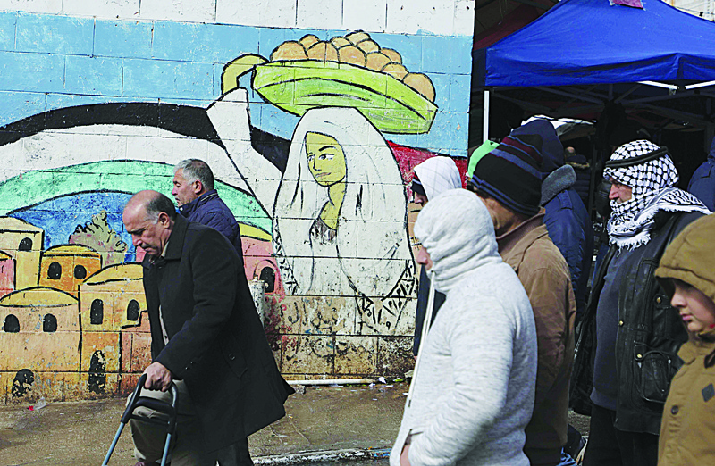Palestinians walk past a mural painting in Ramallah in the occupied West Bank on January 24, 2020. - US Vice President Mike Pence has invited Israeli Prime Minister Benjamin Netanyahu and his main election rival to Washington next week to discuss Donald Trump's long-awaited Middle East peace plan. Palestinian leaders have however dismissed the US peace initiative as one-sided. (Photo by ABBAS MOMANI / AFP)