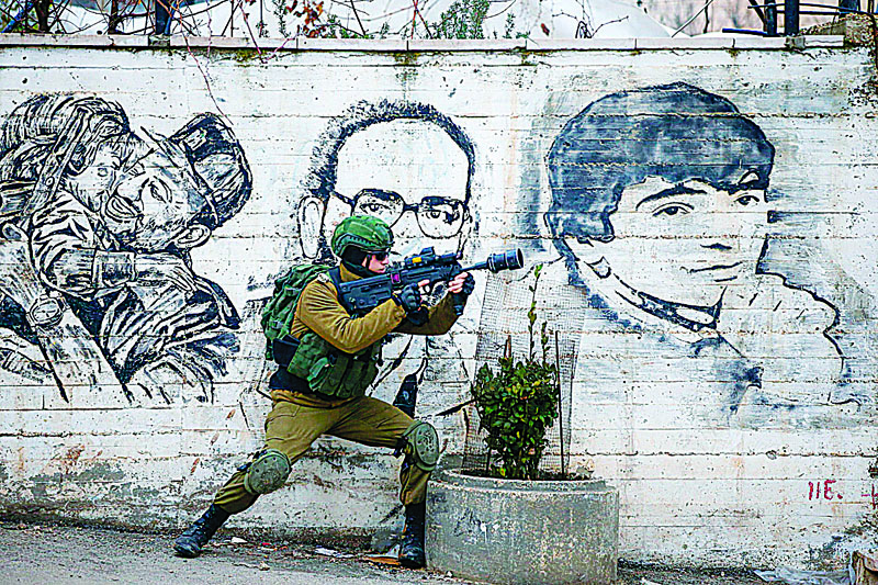 TOPSHOT - An Israeli soldier fires teargas towards Palestinian demonstrators during a demonstration in al-Aroub Palestinian refugee camp, between the West Bank towns of Hebron and Bethlehem, on January 29, 2020. - US President Donald Trump unveiled his controversial Israeli-Palestinian peace deal that staunchly favours Israel but offers Palestinians a pathway to a limited state. (Photo by HAZEM BADER / AFP)
