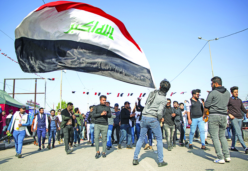 An Iraqi student waves the national flag during ongoing anti-government demonstrations in the southern city of Basra on January 8, 2020, shouting slogans against turning Iraq into a battleground for the conflict between Iran and the US. - For three months, youth-dominated rallies in the capital and Shiite-majority south have condemned Iraq's ruling class as corrupt, inept and beholden to Iran. (Photo by Hussein FALEH / AFP)