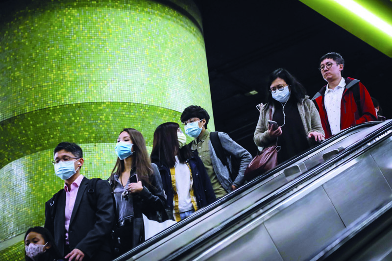 TOPSHOT - Commuters wearing face masks as a precautionary measure to protect against the possible spread of a SARS-like virus outbreak ride an escalator at an MTR subway station ahead of the Chinese New Year in Hong Kong on January 23, 2020. - Hong Kong has turned two holiday camps, including a former military barracks, into quarantine zones for people who may have come into contact with carriers of the Wuhan virus, officials announced on January 23. The international financial hub has been on high alert for the virus, which has killed 17 people since the outbreak started in central China. (Photo by VIVEK PRAKASH / AFP)