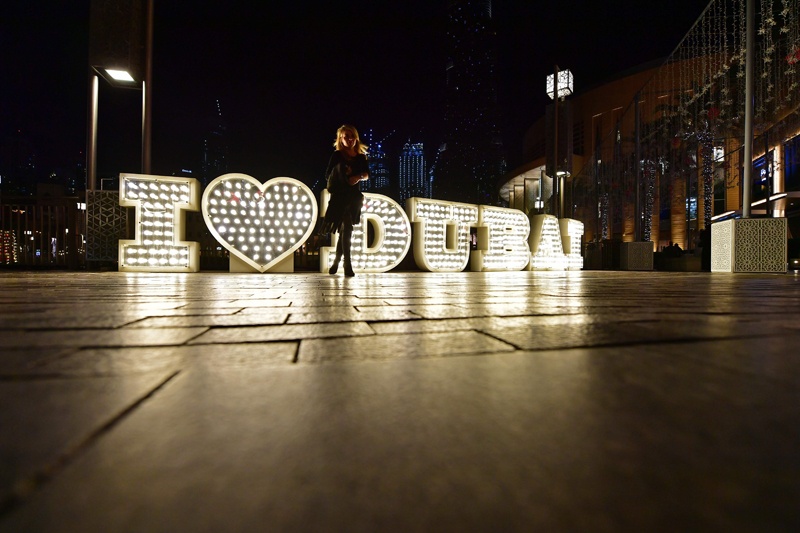 A woman poses for a picture in front of a lit sign in Dubai on January 15, 2020. (Photo by Giuseppe CACACE / AFP)